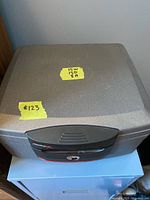 Full view of the SentrySafe fireproof safe showing grey textured exterior, rectangular shape with labeled yellow tape indicating dimensions (15W, 15D, 8H)