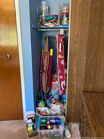 Photo of closet space showing hanging storage containers, rolls of wrapping paper, gift bags and assorted ribbons.
