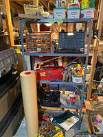 Full view of metal shelving unit with assorted tools, organizer drawer, toolbox, various hand tools, and workshop supplies.