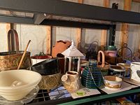 Photo of various planter pots and garden accessories on shelf showing different materials and shapes