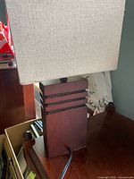 Close-up image showing the dark wood base with horizontal groove accents and rectangular fabric shade with minor wear.