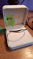 Bracelet displayed inside a white jewelry gift box with a note labeled #91 on green tape.