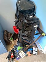 Photo showing Adidas backpacks and duffle bag, shopping tote, and assorted travel accessories placed on the floor against a wall.