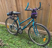 Blue Trek Voyager mountain bike shown full side angle, with front handlebar bag and rear cargo net attached.