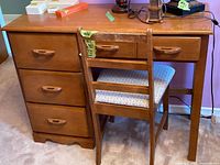 Front view of medium brown wooden desk with four drawers and a matching chair with a patterned cushioned seat.