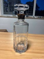 Front view of clear faceted glass decanter with stopper inserted