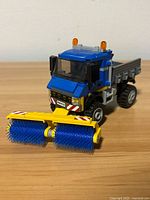 Front three-quarter view of assembled LEGO street sweeper with brush attachment