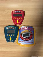 Red Pocket Poker, teal Pocket Blackjack 21, and sealed red Blackjack Keychain Casino keychain game on wood surface