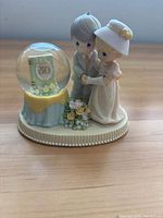 Front view of Precious Moments anniversary figurine showing couple and snow globe