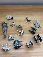 Group view of 13 Star Wars miniature spacecraft on wooden surface