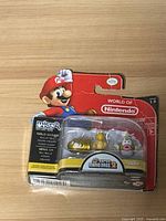 Front of sealed blister pack showing Mario header card and two gold figures on Super Mario Bros. 2 base
