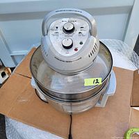 Full view of Big Boss oil-less air fryer showing glass bowl with handle and attached control unit on top with dials and buttons.