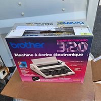 Photo of the original packaging box for Brother Correctronic 320 electronic typewriter. The box shows slight wear and tear with creases and a worn opening flap.
