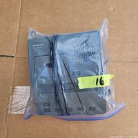 Photo of the Dictaphone 3740 device placed inside a clear plastic bag on a cardboard surface. The black device has visible buttons and attached cord.