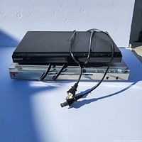 Photo showing two DVD players stacked, Sony on top and Onida below, both with attached power cords.