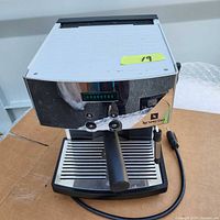 Full front view of Nespresso D300 coffee machine on a cardboard surface, showing portafilter handle and power cord.