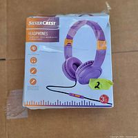 Front of SilverCrest headphones box showing purple headphones with orange accents and wired audio jack with in-line controls.