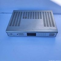 Front and top view of the silver Sirius SR-H550 satellite radio tuner receiver showing ventilation slots and control buttons.