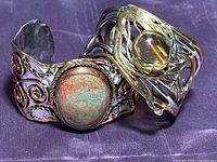 Two mixed metal cuff bracelets side by side showing overall design and stones
