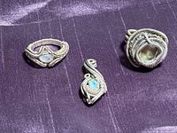 Three sterling silver wire-wrapped pieces displayed on fabric