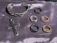 Group shot of cuff bracelet, cross pendant and five rings