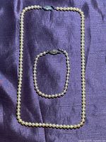 Full view of necklace and bracelet on fabric background