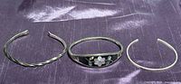 All three bracelets side by side: twisted sterling cuff, Alpaca hinged inlay bangle, plain sterling cuff