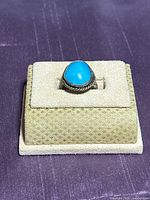 Front view of sterling silver ring with turquoise cabochon on display stand