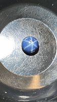 Top view of the round blue star sapphire cabochon showing the distinct six-ray star and deep blue color.