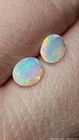 Close-up photo of a pair of natural faceted Ethiopian opals showing vibrant multicolored play of color.