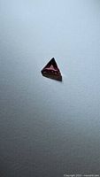 Single purple-orange fancy triangle cut Tanzanian sapphire on neutral background.