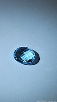 Close-up image of the oval-shaped sky blue topaz gemstone showing the checkerboard cut facets reflecting light.