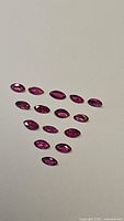 Main image showing 15 natural untreated rubies marquise cut approximately 4x2mm arranged on a plain surface.