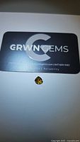 Photo showing the pear cut whiskey orange tourmaline gemstone next to a GRWN GEMS branded card for size reference and authenticity.