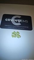 Photo showing cluster of demantoid garnet crystals alongside a CRWN Gems business card for scale and authenticity branding