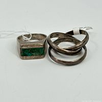 Two vintage sterling silver rings shown side by side. One has crushed turquoise inlay, the other is plain band.