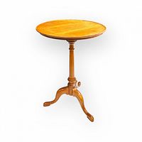 Full view of circular wooden table showing top, pedestal, and tripod legs, against a white background.
