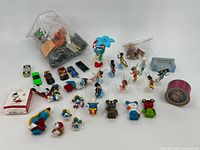 Wide view of collection showing all figurines, cars and other character toys arranged on a white backdrop.