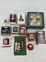 Full view of all 14 Christmas ornaments, including boxed Hallmark Keepsake ornaments, Asian female figure ornaments, a red rose, and a small Mickey Mouse figurine ornament.