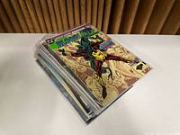 Stack of comic books including Bloodlines Annual on top, in a plastic protective sleeve, showing colorful graphic cover art.