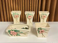 Five floral ceramic pots arranged on table, front view showing all sizes and shape variety