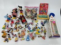 Full group of Disney-themed figurines, small dolls, toy car, and sticker house on white background.