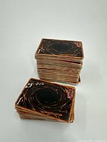 Photo showing two stacks of Yu Gi Oh cards from the back with swirl pattern design.