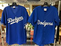 Two blue Dodgers T-Shirts on hangers showing front Dodgers script logo.