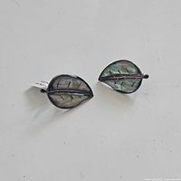 Pair of leaf shaped sterling silver earrings with abalone inlay displayed on a white background.