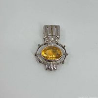 Front view of sterling silver pendant with oval yellow topaz gemstone in decorative setting.