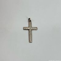 Front view of the sterling silver cross pendant showing textured linear design and bail for attachment.