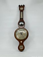 Full front view of the wooden vintage barometer showing the entire instrument from top to bottom with the thermometer, pressure dial, and bottom gauge visible.