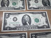 Front side of several 1976 $2 bills showing Jefferson portrait and serial E06717152A