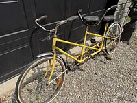Full view of yellow Schwinn tandem bicycle against garage door